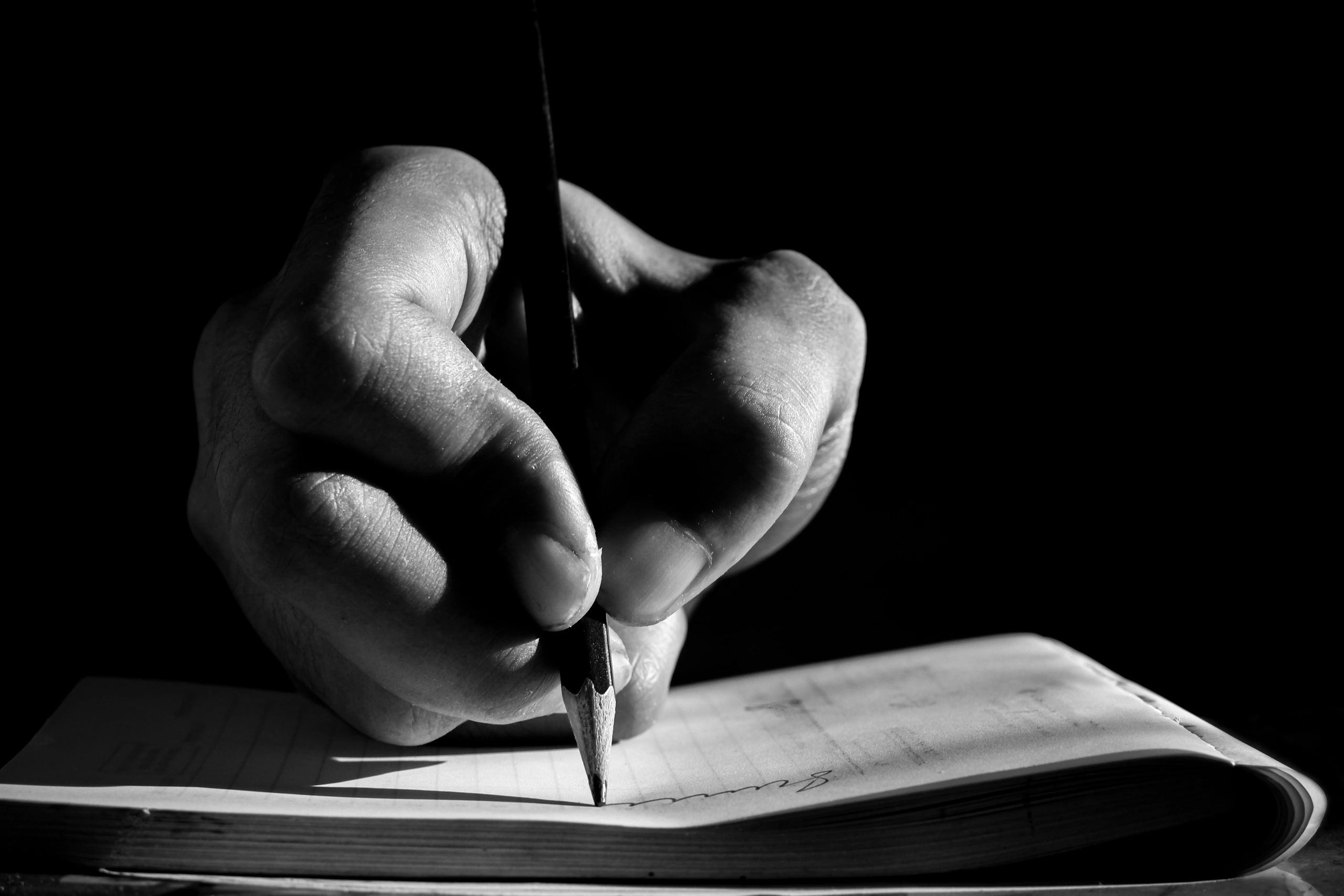 Close-up of a hand writing in a notebook (black and white)
